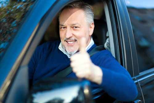 A happy customer smiles while testing a car at a Connecticut motor vehicle dealer