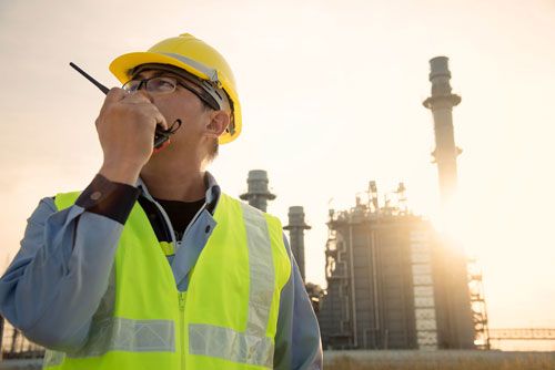 A contractor stands in front of a power plant