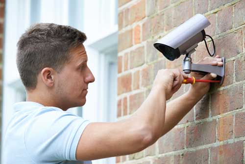A worker installs a security alarm system.