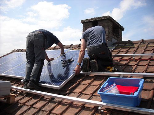 Workers install a solar energy system on a house