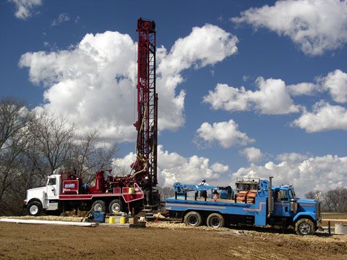 Workers operate a water well drill